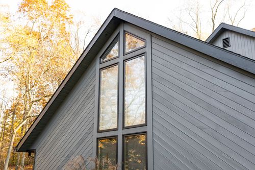 Close-up gable exterior with diagonal board siding and tall peaked window