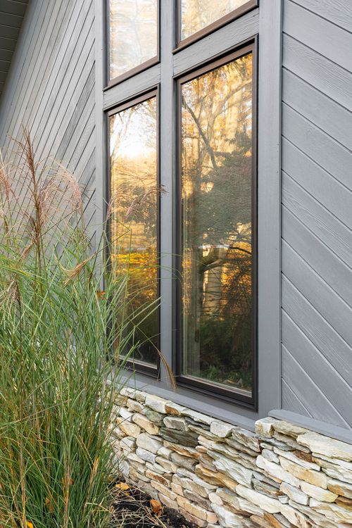 Close-up of a tall paned window with dark trim on diagonal gray siding