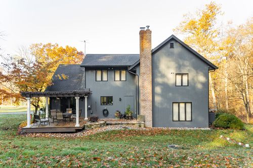 Home exterior with brick chimney, pergola patio and gray board-and-batten siding