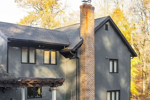 Close-up exterior of a tall brick chimney against gray gabled siding