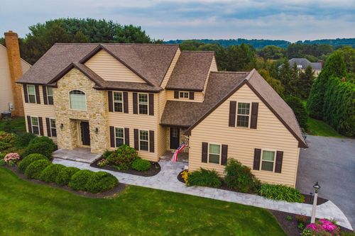 Aerial view of a tan stone-front two-story home with manicured landscaping