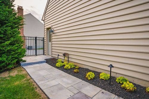 Side yard walkway with stone pavers, black gate and manicured landscaping beds