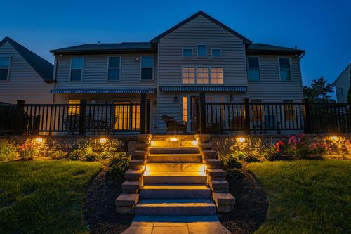 Home exterior at dusk with illuminated stone steps and landscape lighting
