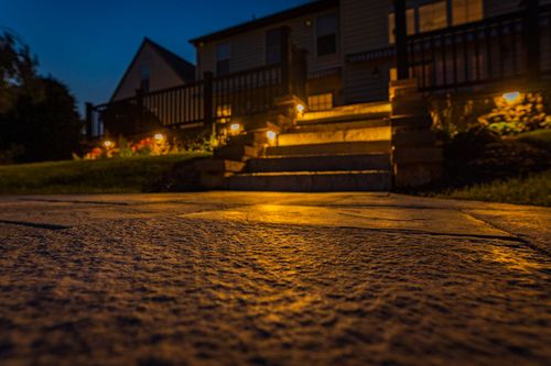 Low-angle view of an illuminated stone walkway leading to a home's front steps at night