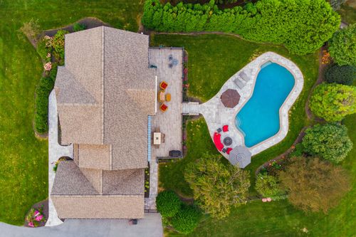 Aerial view of a home with covered deck, freeform pool and stone patio surround
