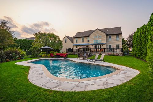 Aerial dusk view of a freeform pool, patio furniture and multi-level deck by the home