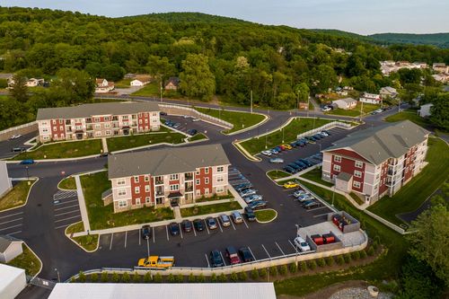 Aerial view of a multi-building brick apartment complex surrounded by wooded hills