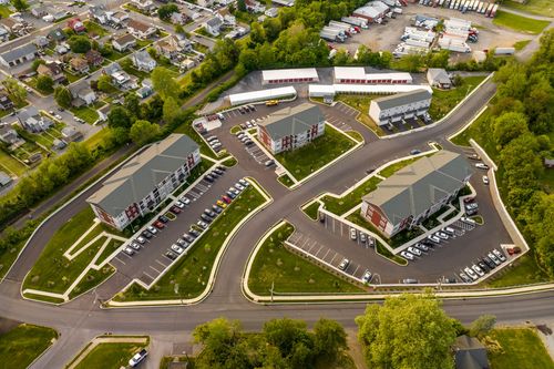 Aerial view of multiple brick apartment buildings and parking areas near a warehouse