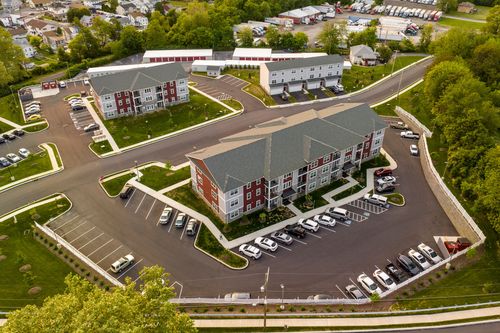 Aerial view of red-brick apartment buildings with parking lots and green rooftops