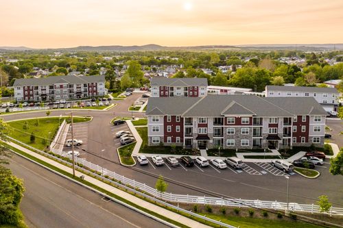 Aerial sunset view of apartment buildings with white picket fencing and parking lots