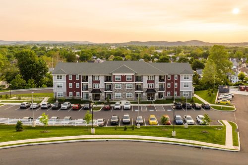 Aerial sunset view of a red-brick apartment building with balconies and a full parking lot
