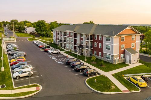 Aerial sunset view of a red and tan apartment building with balconies and landscaped grounds