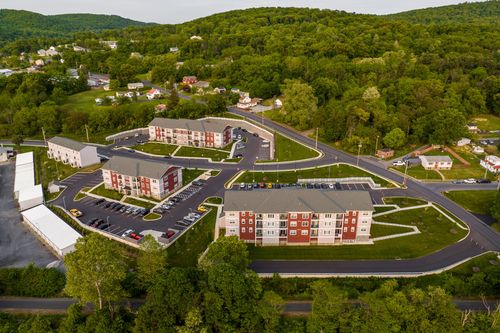 Aerial view of a multi-building apartment complex with landscaped courtyards and hills beyond