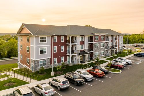 Aerial sunset view of a red and tan apartment building with balconies and parking