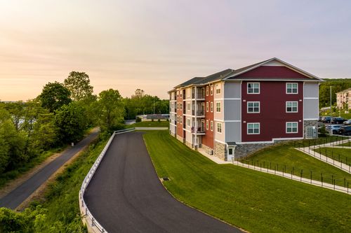 Aerial sunset view of a red apartment building with balconies beside a curved access road