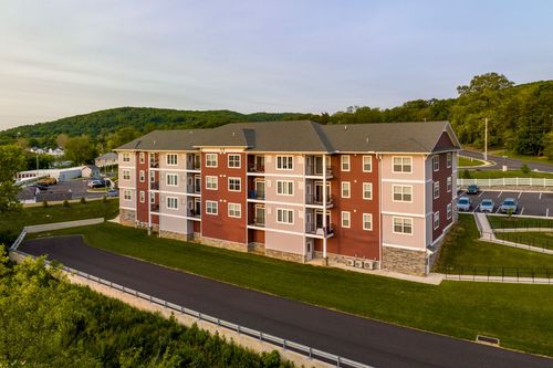 Aerial view of a red and tan apartment building with stone base along a curved road