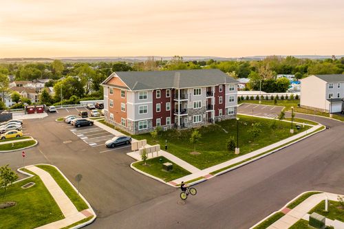 Aerial sunset view of an apartment building with parking lot and a cyclist on the path