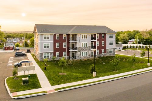 Aerial sunset view of a red apartment building with landscaped entrance and full parking