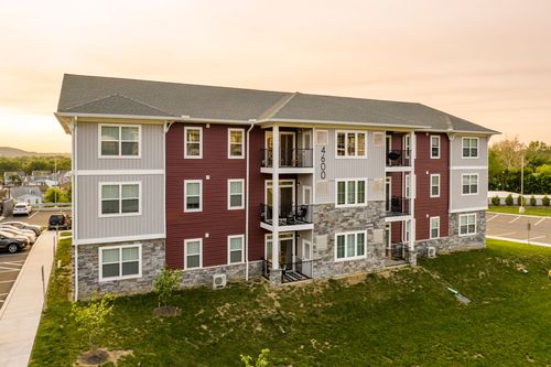 Aerial sunset view of a red-brick apartment building with balconies and stone base