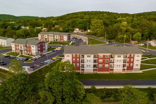 Aerial view of red-brick apartment buildings and parking lots bordered by dense woods