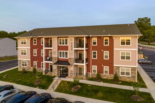 Aerial sunset view of a red apartment building with covered entry and stone base