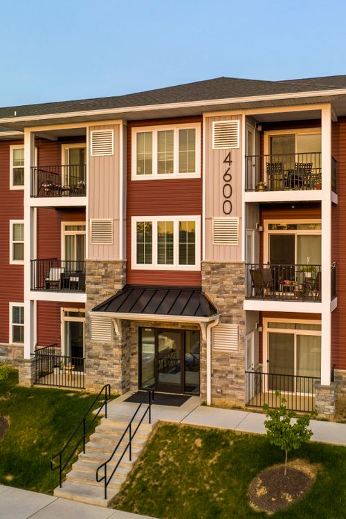 Close-up exterior of a red apartment building with private balconies and stone base