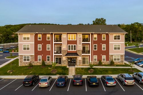 Aerial sunset view of a red apartment building with covered entrance and parked cars