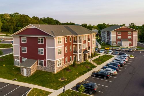 Aerial view of a red and tan apartment building with covered entry and parking lot