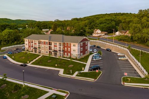 Aerial sunset view of an apartment building with white picket fencing along the drive