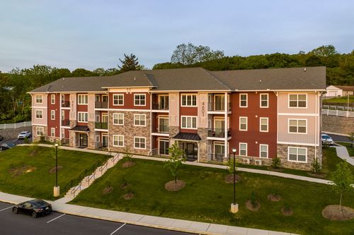 Aerial view of a red apartment building with stone base and a covered walkway entrance