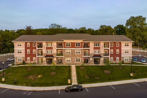 Aerial view of a red and tan apartment building with symmetrical walkways and parking