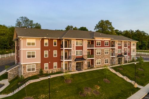 Aerial view of a red and tan apartment building with covered entrances and stone accents