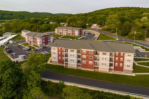 Aerial view of a red and tan brick apartment complex with curved driveways and greenery