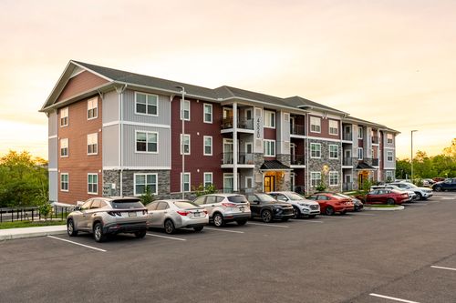 Row of SUVs parked beside a red and gray apartment building under an orange sunset sky