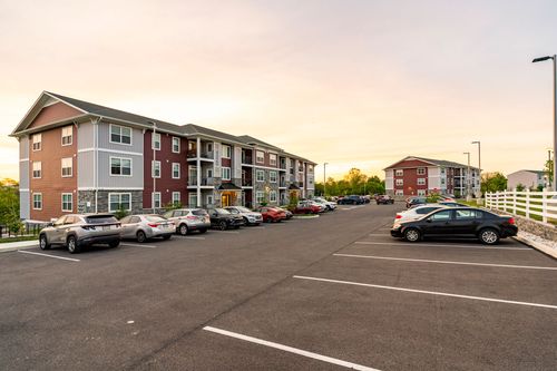 Apartment building exterior reflecting a warm orange sunset across the parking lot