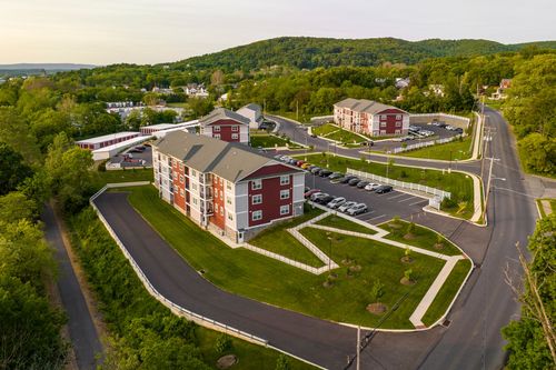 Aerial view of red-brick apartment buildings with landscaped grounds and winding drives
