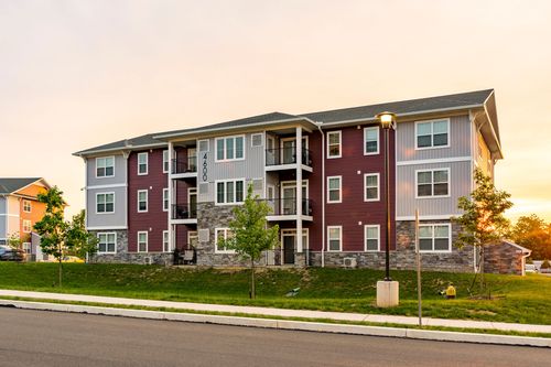 Apartment building exterior with young street trees along the sidewalk under a warm sunset sky
