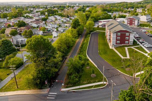 Aerial view of an apartment building beside a residential street and mature trees
