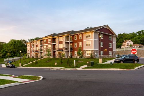 Apartment building on a hillside with a stop sign and van parked in the foreground at dusk