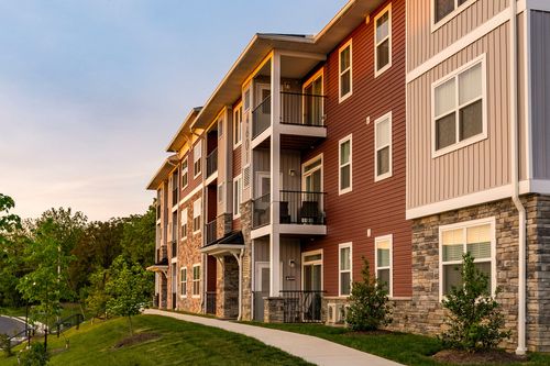 Long elevation of an apartment building with young street trees under a fading dusk sky