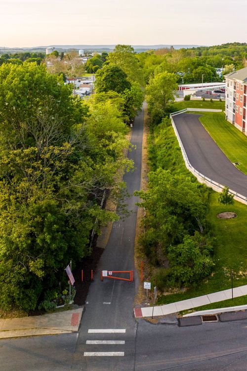 Aerial view of a tree-lined entrance drive with gated access to an apartment complex