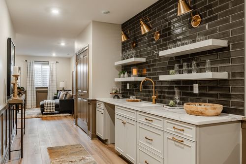 Wet bar counter with black tile backsplash, gold pendant sconces and open shelving for glassware