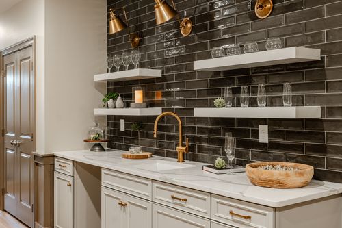 Wet bar corner with black subway tile, floating shelves and gold accent lighting