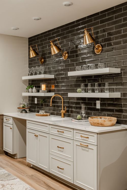 Wet bar sink with a gold faucet, marble countertop and black tile backsplash