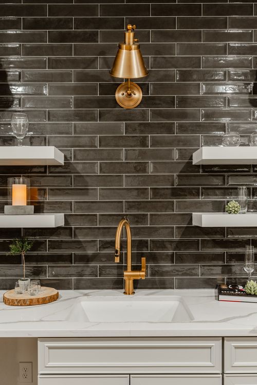 Wet bar sink detail with a gold faucet, wine glasses and marble countertop