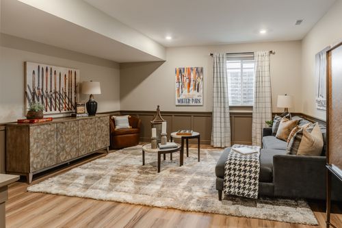 Basement sitting area with ski-themed artwork, a leather chair and a houndstooth throw blanket