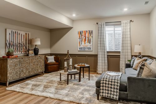 Basement family room with vintage ski posters, a wood console and a gray sectional sofa