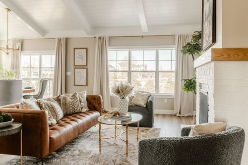 White painted brick fireplace with a wood mantel, potted plant and pampas grass arrangement