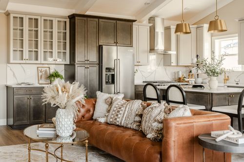 Kitchen with dark cabinetry, marble backsplash, stainless fridge and an island with black chairs