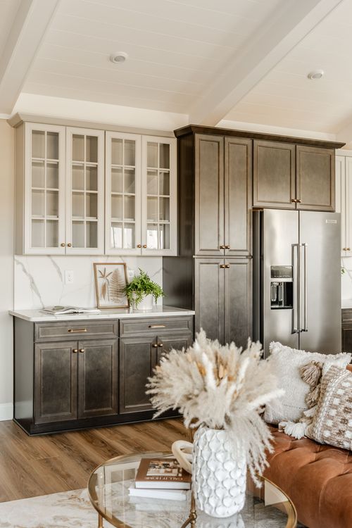 Kitchen with a stainless refrigerator, dark tall pantry cabinet and white upper cabinetry